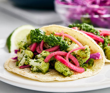 Two cauliflower tacos with onions and chimichurri sauce