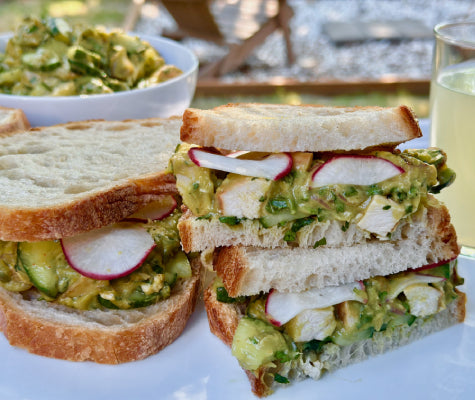 Cross-section of Newman's Own avocado salad sandwiches outdoors, with lemonade in the background