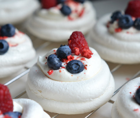 Red, white, and blueberry pavlova for Independence Day -- one central white pavlova topped with whipped cream, blueberries, freeze-dried strawberries, and raspberry