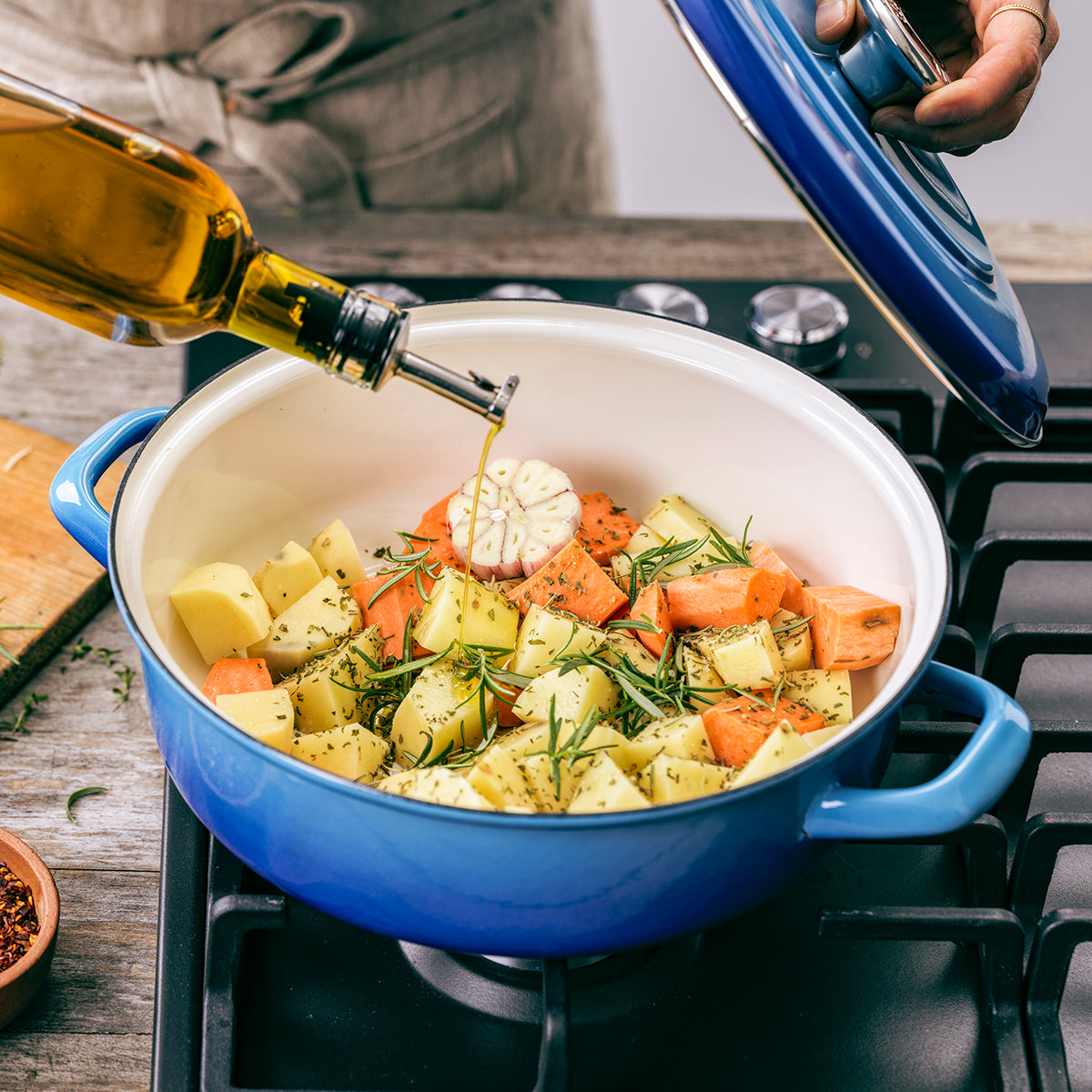 Oil being poured into a vegetable recipe being cooked in the Merten & Storck Enameled Iron 1873 Braiser, 4-Quart in the color Azure Blue.